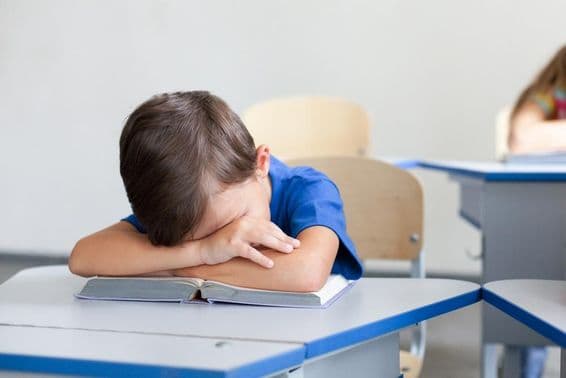 Niño escolar durmiendo durante una clase aburrida.