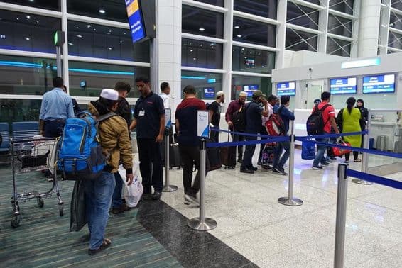 Personas formando fila para abordar en la puerta del Aeropuerto Internacional de Dubái.