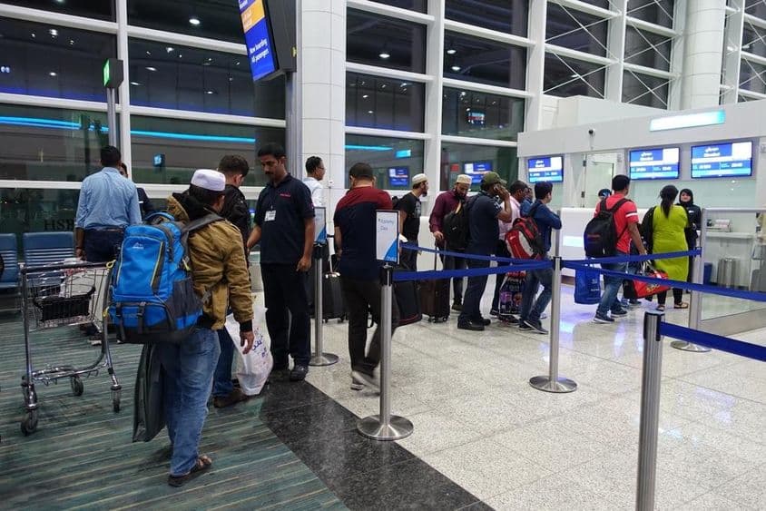 Personas formando fila para abordar en la puerta del Aeropuerto Internacional de Dubái.
