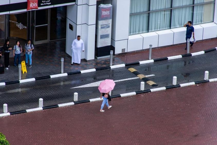 Una niña con un paraguas caminando bajo la lluvia en la ciudad de Dubái.