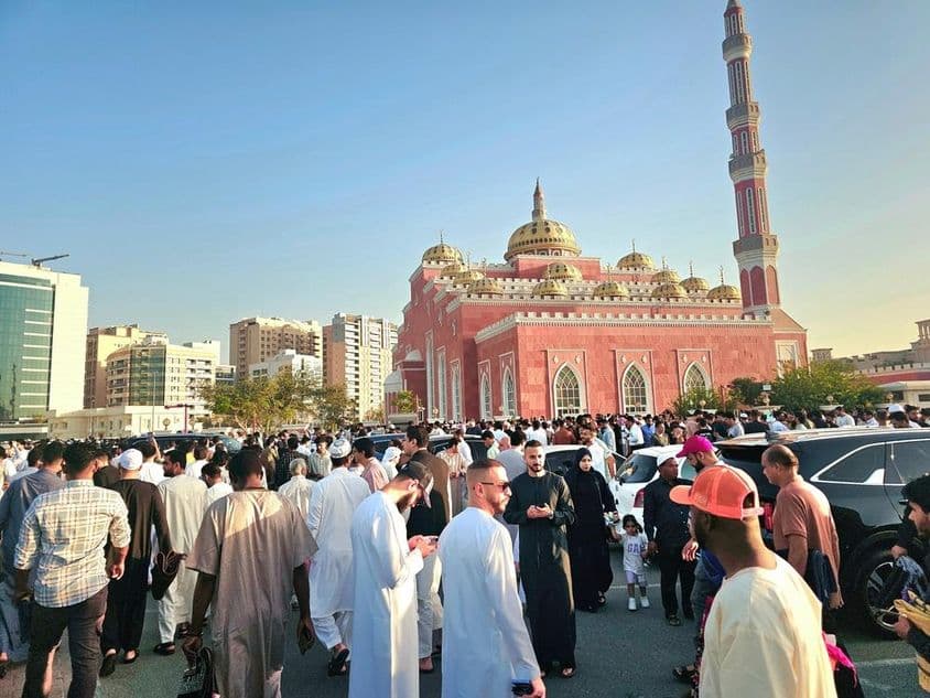 Una gran multitud reunida frente a una majestuosa mezquita con cúpulas y altos minaretes.