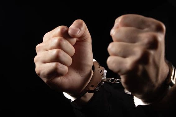 Hombres esposados arrestados por delitos.