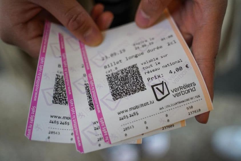 Un joven sosteniendo entradas en su mano.