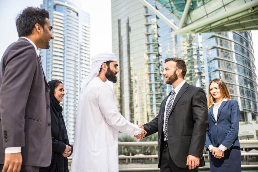 Grupo multinacional de empresarios reuniéndose al aire libre en Dubái.