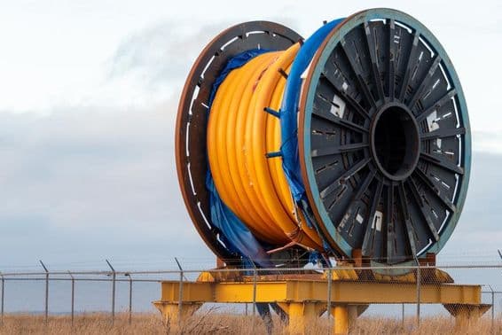 Cable de fibra óptica industrial masivo bajo el agua en un carrete de metal en la cubierta de un barco.