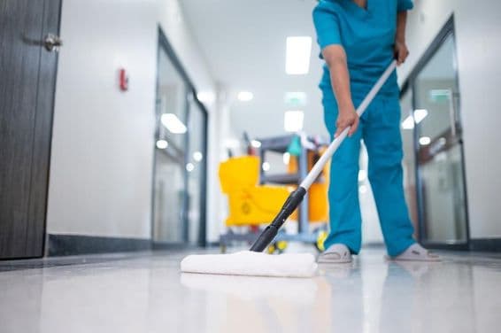 Limpiador trapeando el piso del pasillo.