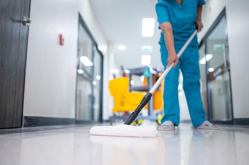 Limpiador trapeando el piso del pasillo.