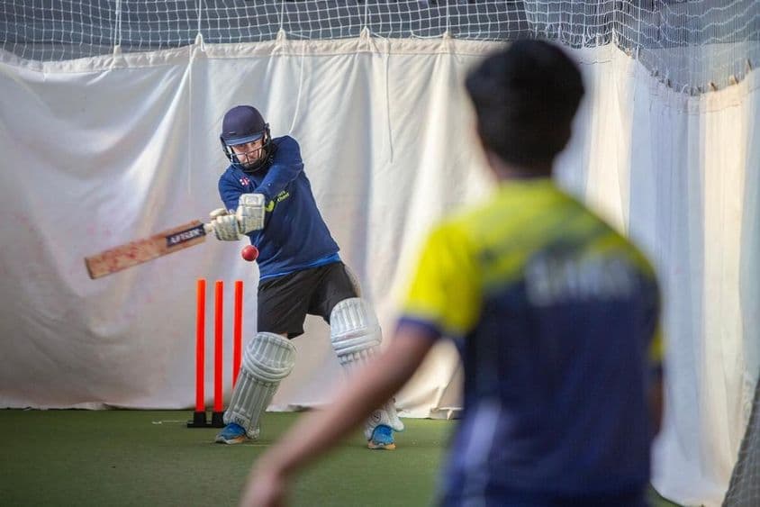 Miembros de un club de cricket en práctica en redes cubiertas de invierno.
