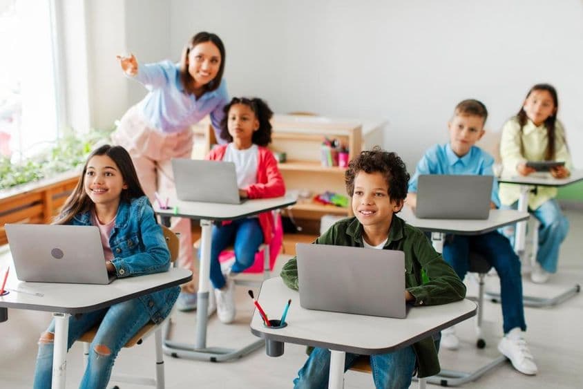 Grupo de niños recibiendo una clase usando computadoras portátiles.
