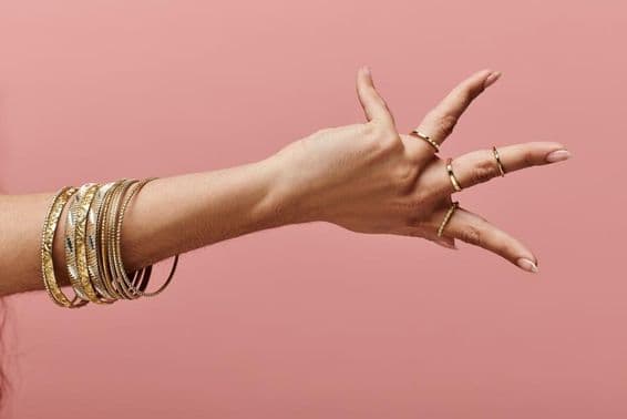 Mujer india posando elegantemente con brazaletes de oro en su muñeca.