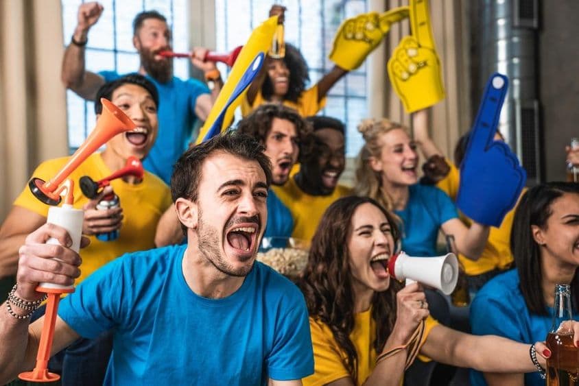 Aficionados al deporte multinacionales y felices viendo el partido en la TV en casa.