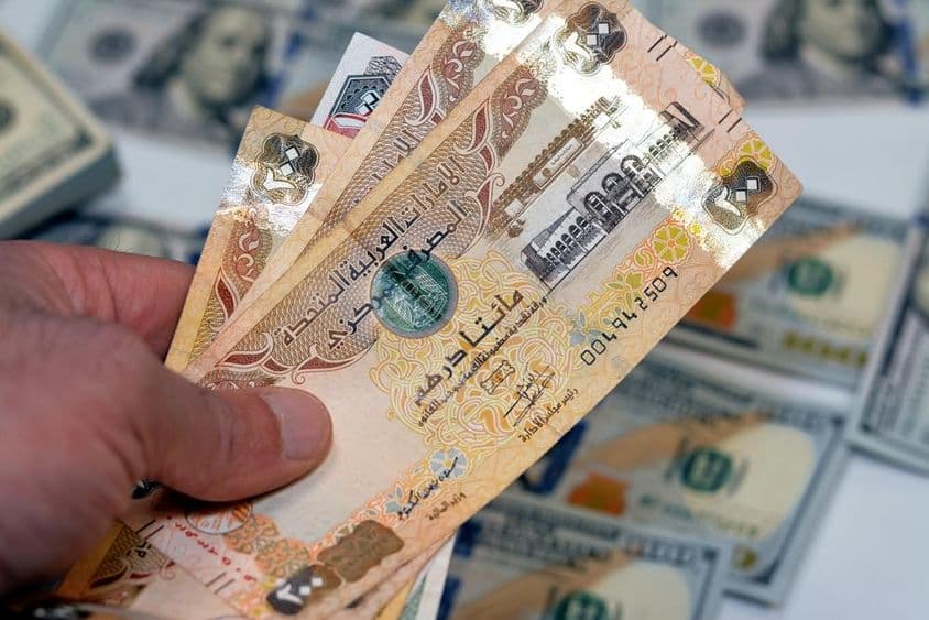 Un hombre sosteniendo un fajo de billetes de 200 dirhams de Emiratos Árabes Unidos.
