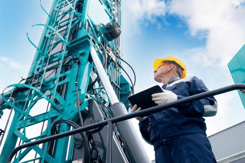 Operador industrial usando una tablet digital para controlar una plataforma de perforación.
