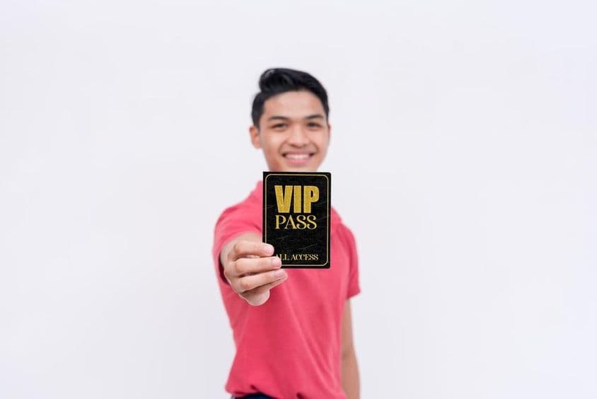 Un hombre feliz sosteniendo un boleto o identificación VIP.