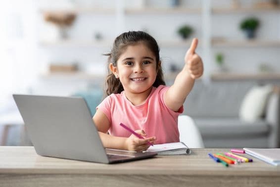 Niña árabe aprendiendo en casa con un portátil, mostrando el pulgar arriba.