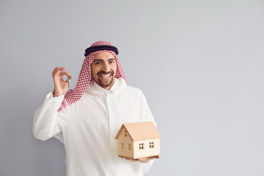 Agente inmobiliario árabe sosteniendo un modelo de casa.