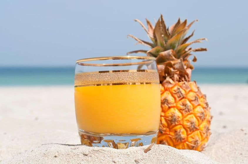 Un vaso de jugo de piña en la playa.