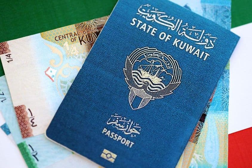 Dinar kuwaití y pasaporte sobre una mesa.
