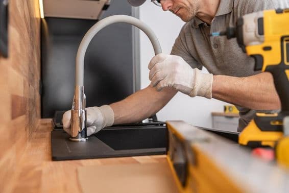 Un fontanero instalando un grifo de cocina.