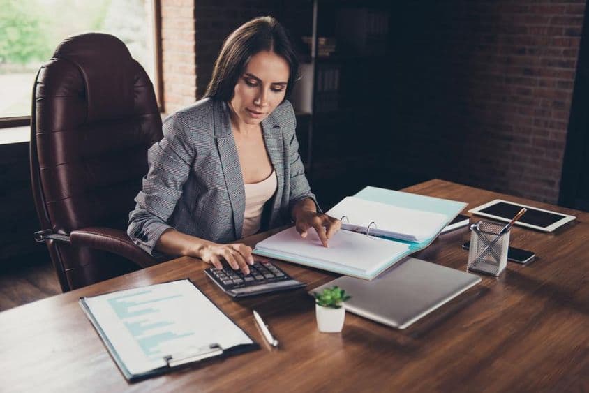 Mujer exitosa revisando documentos en un escritorio antes de presentarlos a la autoridad fiscal.