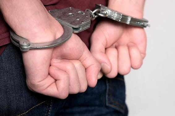 Un delincuente esposado arrestado por delitos.
