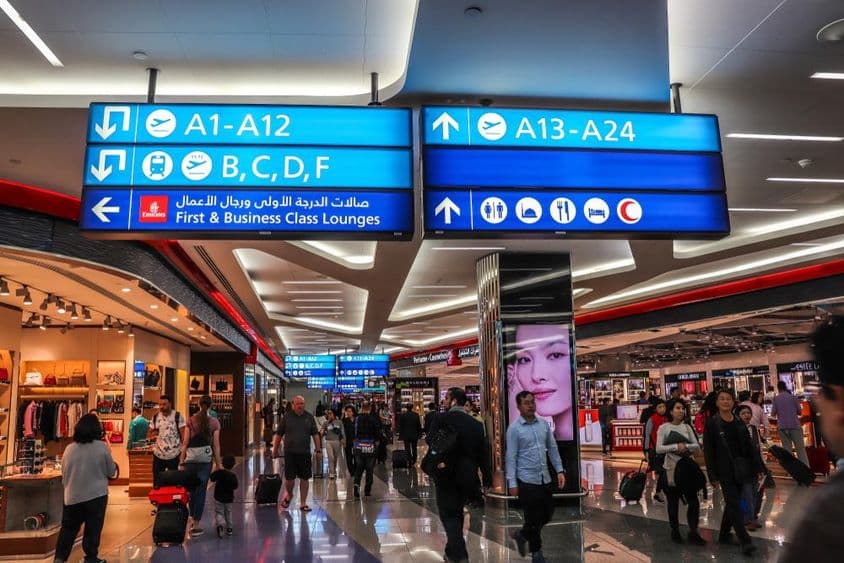Pasajeros caminando hacia las puertas de salida en el Aeropuerto Internacional de Dubái (DXB).