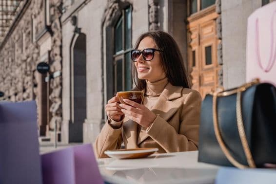 Una chica con gafas de sol bebiendo café.