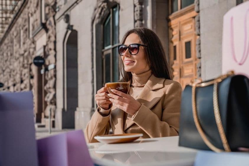 Una chica con gafas de sol bebiendo café.