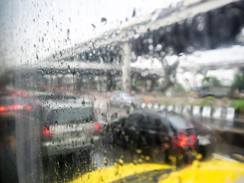 Tráfico en un día lluvioso con gotas de lluvia en la ventana del coche.