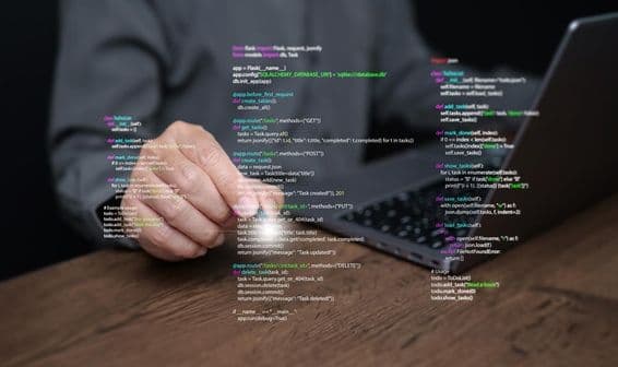 Manos de un programador sobre un portátil con código.