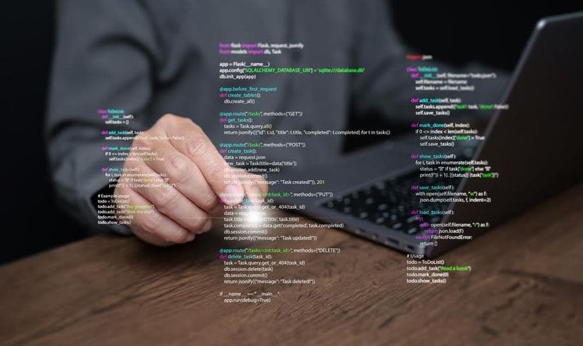 Manos de un programador sobre un portátil con código.
