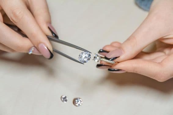 Las manos de una mujer joyera sosteniendo una piedra preciosa.