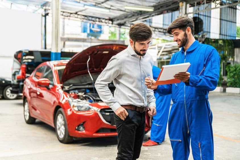 Mecánico mostrando lista de verificación de inspección de coche a un cliente.