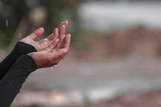 Una mujer rezando con las manos por lluvia.