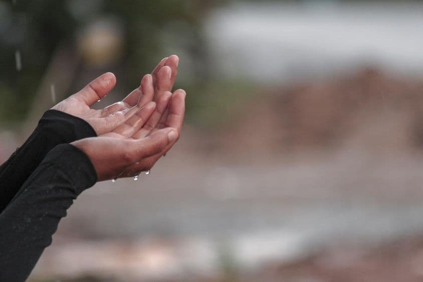 Una mujer rezando con las manos por lluvia.