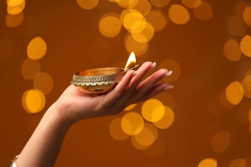 Mujer sosteniendo una lámpara de Diwali encendida