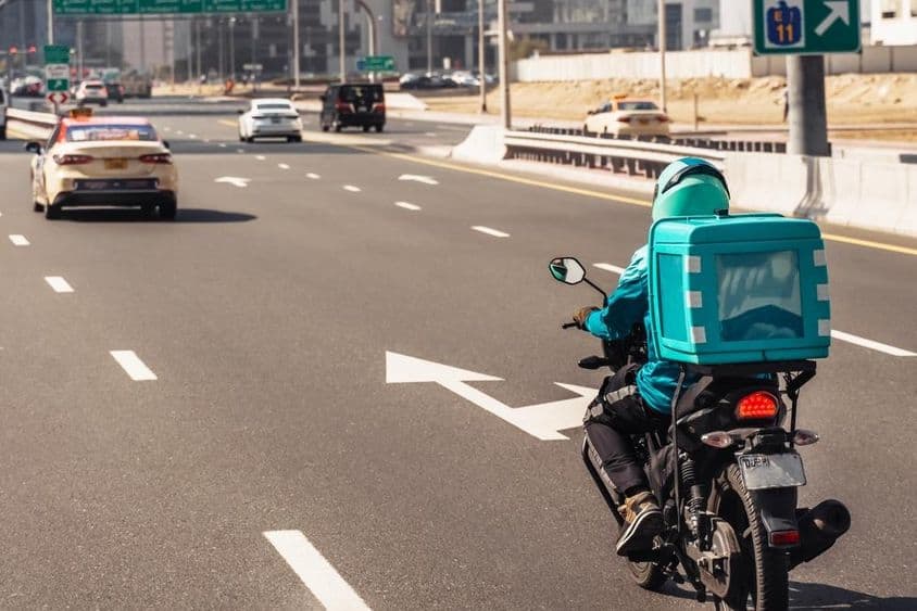 Dubái, hombre en motocicleta para entrega de comida en línea.