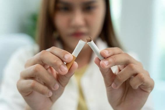 No fumar, una mujer rompe un cigarrillo por la mitad.