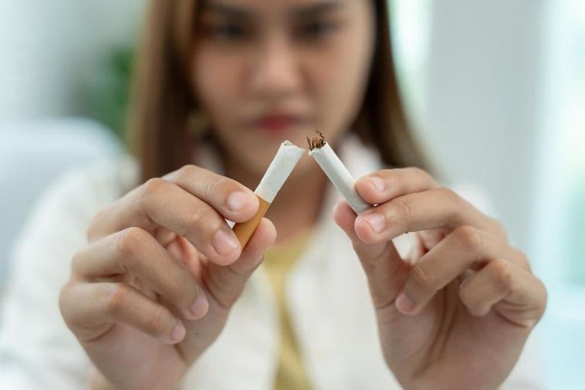 No fumar, una mujer rompe un cigarrillo por la mitad.