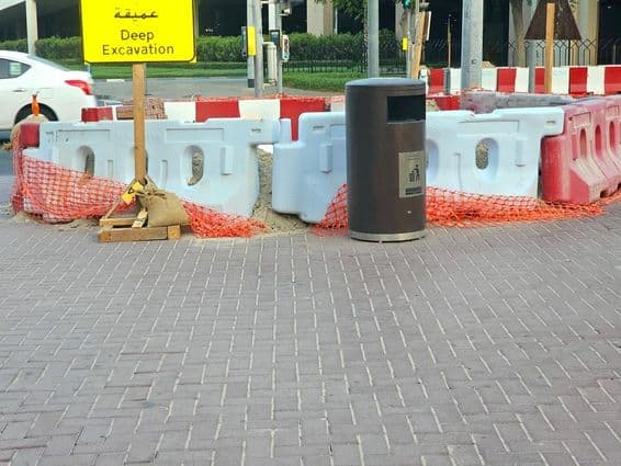 La reparación de la carretera está rodeada por barreras plásticas y una red de seguridad naranja.