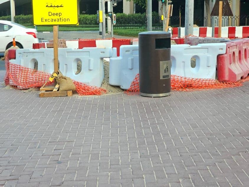 La reparación de la carretera está rodeada por barreras plásticas y una red de seguridad naranja.