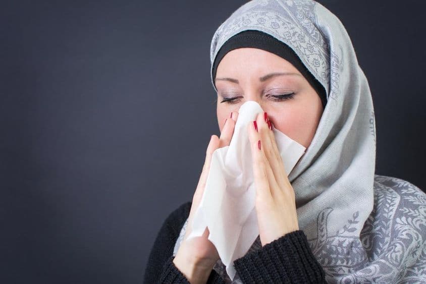 Una hermosa mujer musulmana con un resfriado y goteo nasal.