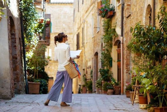 Una mujer con un mapa y un sombrero de paja, disfrutando del paseo en Toscana, Italia.