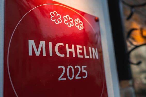 Una placa Michelin 2025 de tres estrellas roja en una pared de color claro.