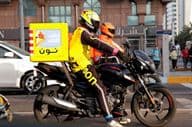 Repartidor en motocicleta entregando en una calle de Dubai.