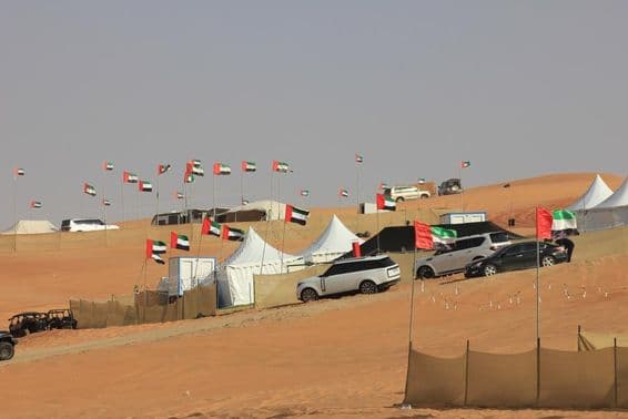 Vehículos todoterreno y campamento salvaje sobre enormes dunas de arena.