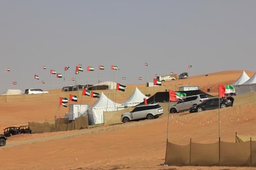Vehículos todoterreno y campamento salvaje sobre enormes dunas de arena.