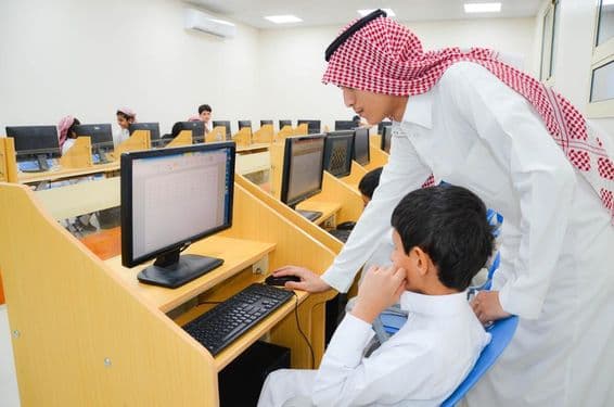 En un Laboratorio de Educación Computacional, un maestro instruye a estudiantes sobre el uso de computadoras.