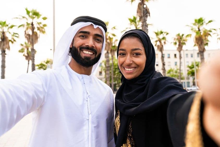 Pareja árabe tradicional con atuendo emiratí en una cita al aire libre.