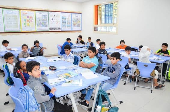 Un aula donde un grupo de estudiantes y su maestro están en una lección.